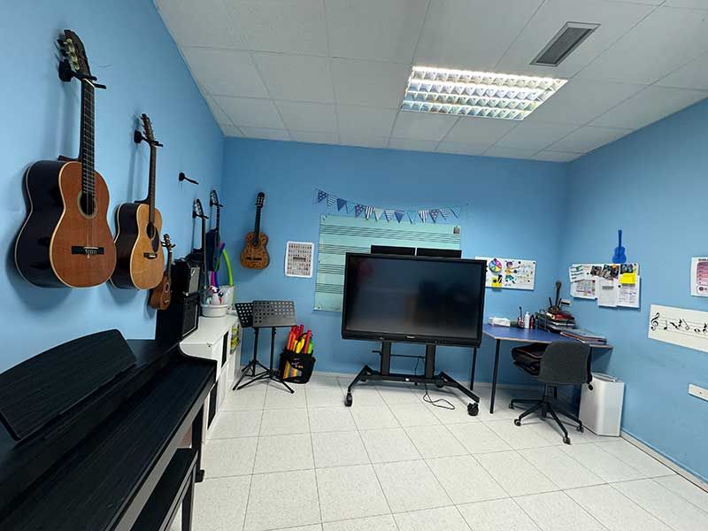 Aula azul con guitarras y piano para clases de música