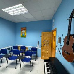 Aula azul con sillas, guitarra y piano para clases