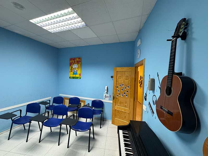 Aula azul con sillas, guitarra y piano para clases