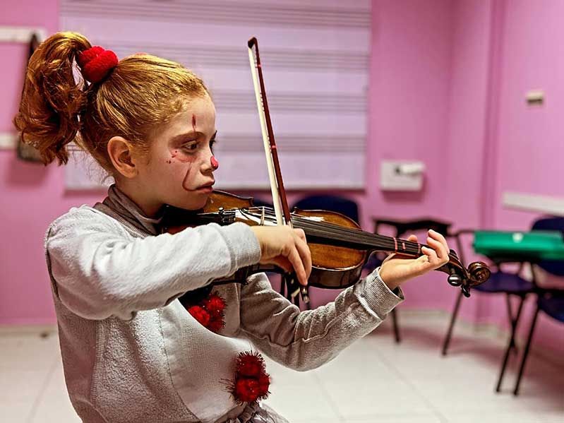 Niña violinista disfrazada de payaso